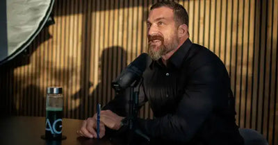 A man with a beard and dark shirt speaking into a microphone.