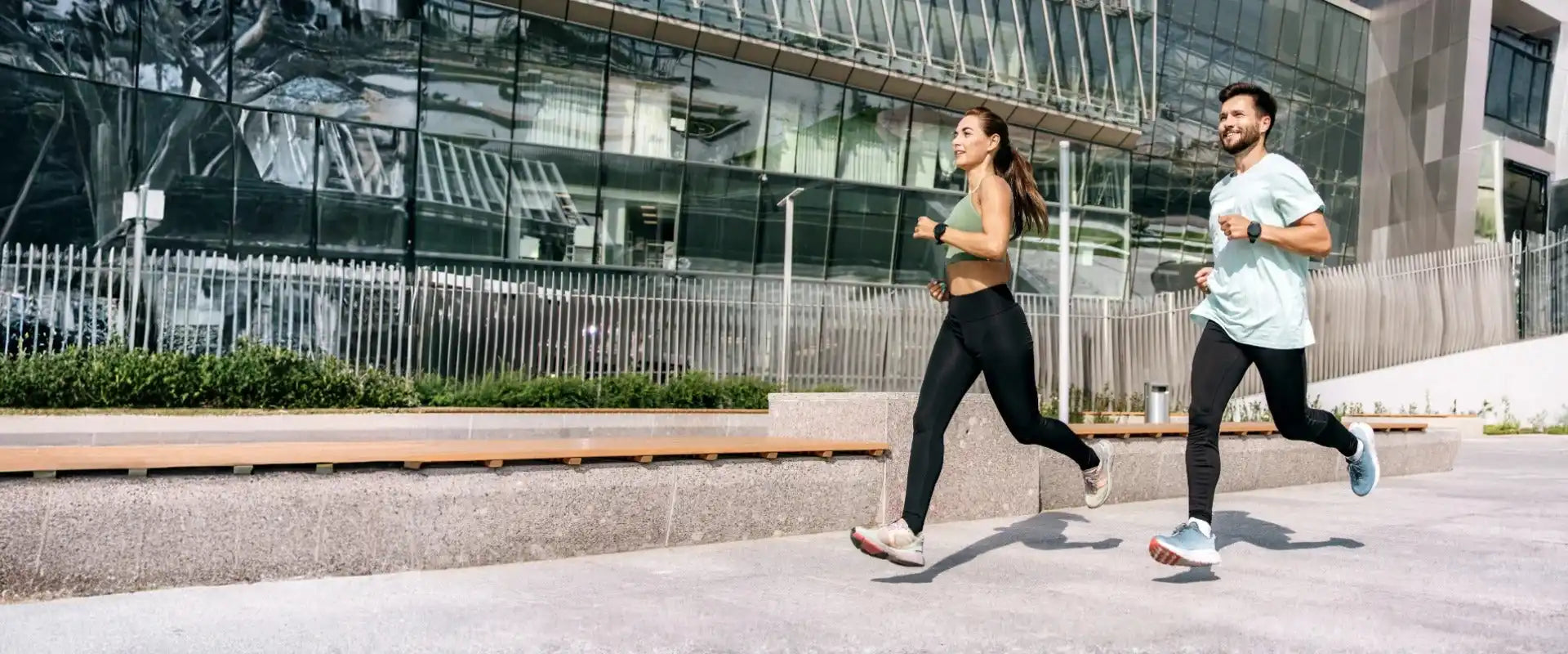Two people running outdoors in athletic wear.
