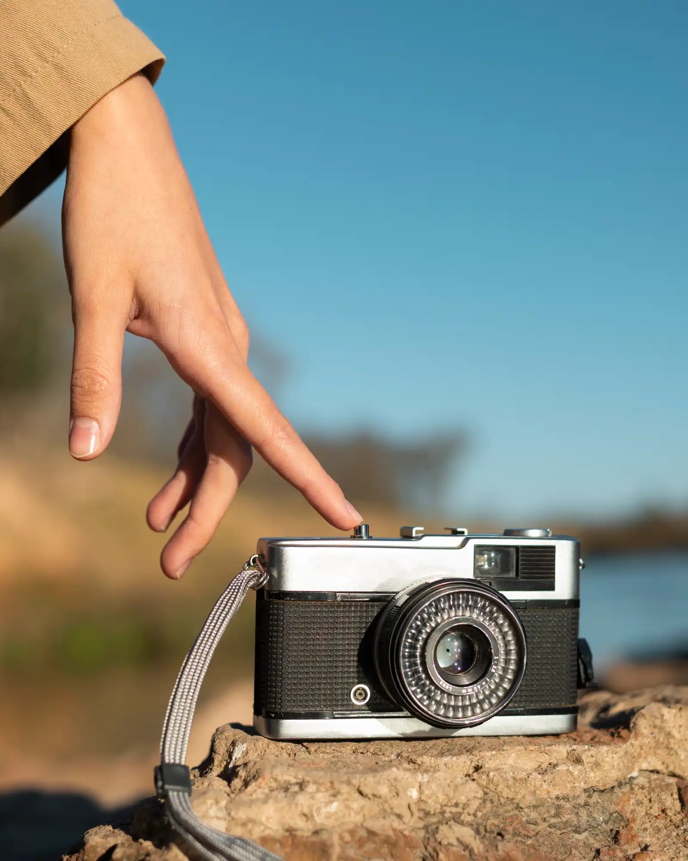 A vintage film camera with a silver top and black body, and a patterned lens.